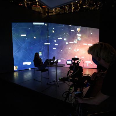 Silhouetted actor and camera operator in front of a video projected background